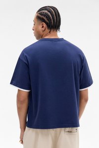 Marineblå oversized t-shirt med korte ærmer og hvid kant. Blød tekstur, afslappet pasform med rund halsudskæring.