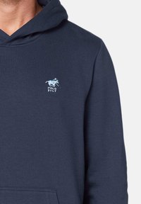 Navy blue hoodie made of soft fabric featuring a kangaroo pocket and a light blue embroidered logo of a horse and "POLO SYLT" on the chest.
