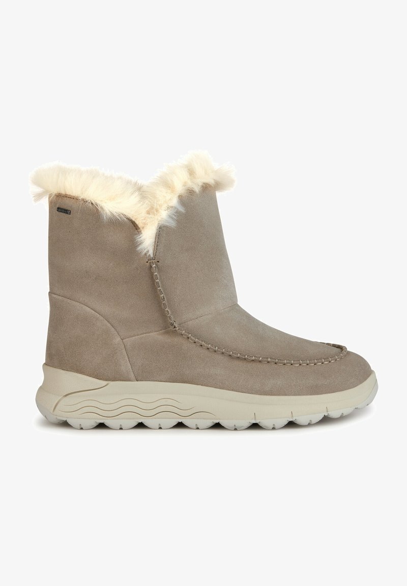 Tan suède enkellaarsjes met een fluffy crèmekleurige nepbont kraag, gestikte details en een lichte rubberen zool met een textuurpatroon voor grip.