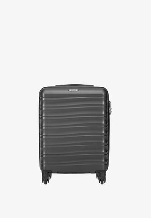Czarna walizka o twardej skorupie z poziomymi falistymi wzorami, czterema obrotowymi kółkami i górnym uchwytem.