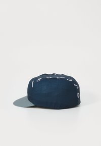 Navy cap made of textured fabric with a light gray brim. Features white letters on the front. Structured shape with a rounded top.
