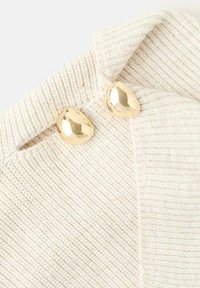 Tessuto lavorato a maglia bianco sporco con una texture a coste, caratterizzato da due bottoni ovali di color oro lucido vicino al colletto.