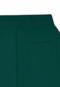 Grønne joggebukser med ribbestrikket midje, med en enkel baklomme. Glatt tekstur og enkel design uten synlige mønstre.