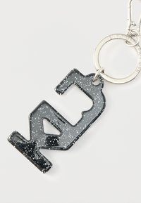 Czarny akrylowy brelok w kształcie liczby 24, ozdobiony srebrnymi brokatowymi akcentami, przymocowany do srebrnego metalowego kółka z klipsem.