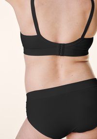Czarny stanik sportowy z cienkimi ramiączkami i zapięciem na plecach, w połączeniu z czarnymi majtkami o wysokim stanie. Gładka tekstura, minimalistyczny design.