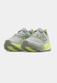 Graue Sportschuhe mit einem Mesh-Obermaterial, fluoreszierend grünen Akzenten und einer strukturierten Sohle für besseren Halt. Verfügen über eine Schutzkappe an der Spitze.