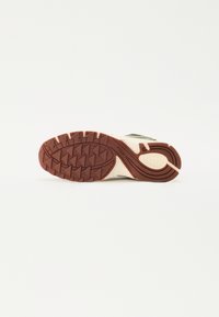 Semelle de chaussure en caoutchouc marron avec des motifs de traction profonds, design incurvé, mettant en valeur une semelle intermédiaire texturée de couleur claire et des bords renforcés.