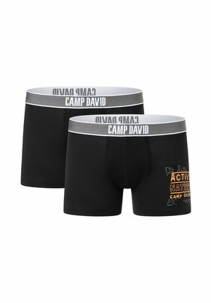 Deux boxers noirs pour hommes avec des ceintures grises étiquetées "CAMP DAVID" et un texte orange sur une jambe indiquant "ACTIVE NATURE CAMP DAVID."