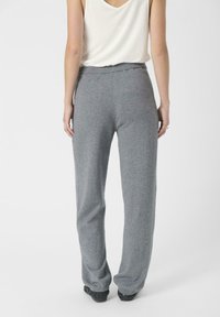 Graue, lässig geschnittene Hose aus weichem Stoff, mit einem elastischen Bund und langen, geraden Beinen, von hinten gezeigt.