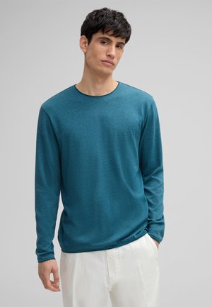 Chemise à manches longues teal avec un col rond, fabriquée à partir d'un tissu texturé. Présente une coupe décontractée avec des coutures et des piqûres minimales.