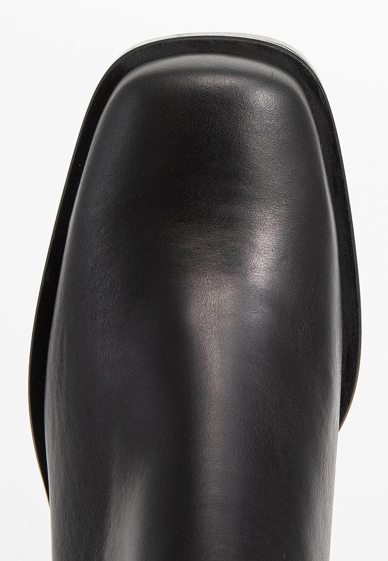 Stivaletto in pelle nera alla caviglia con punta arrotondata, texture liscia e accenti minimi. Presenta un design moderno e elegante con tacco basso.