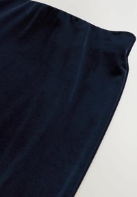 Tessuto in velluto blu navy con una texture liscia, caratterizzato da una morbida lucentezza e un design leggermente drappeggiato lungo i bordi.