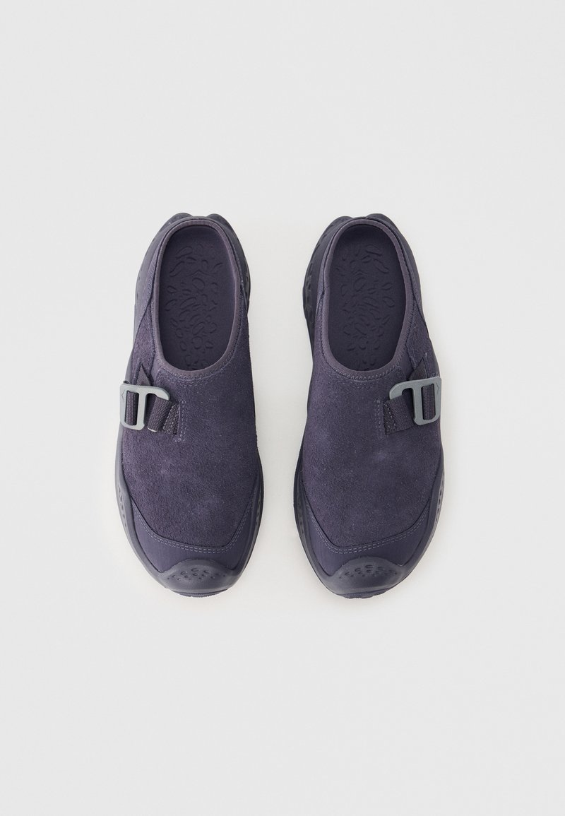 Zapatos mocasín de ante azul marino oscuro con parte superior texturizada, punta redondeada y un adorno de hebilla gris. Suela de goma para agarre y comodidad.