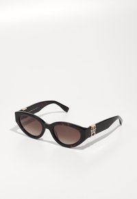 Cat-eye sunglasses with brown gradient lenses, tortoiseshell frame, and gold-tone logo accent on temples. Smooth plastic material.