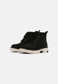 Botas de tobillo de ante negro con suela de goma blanca gruesa, con diseño de cordones y ojales reforzados, con un sutil logotipo en el talón.