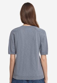 Ljusblått stickat kortärmat tröja med rund hals, med en slät yta och ribbad nederkant och ärmslut. Bakvy visas.