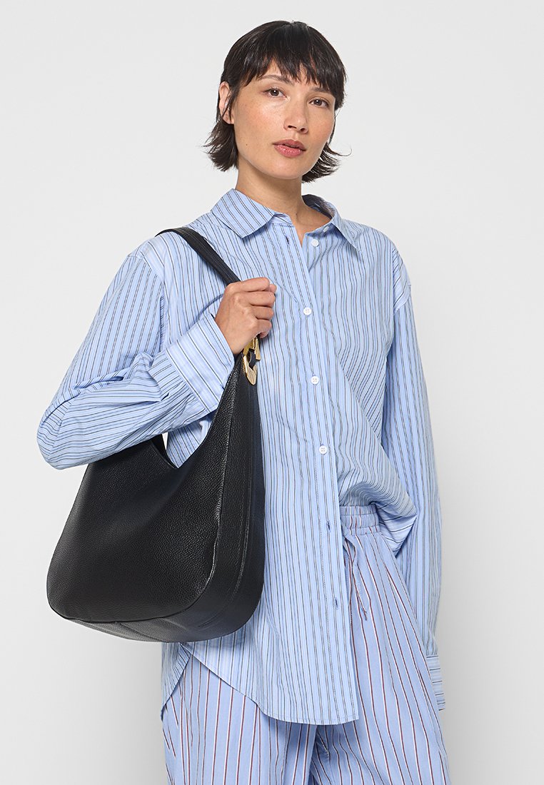 Borsa hobo in pelle nera con una texture liscia e una forma curva. Presenta una tracolla singola e un accento dorato vicino al punto di attacco.