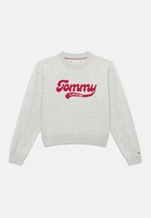 Maglione a maglia grigio chiaro con il testo rosso "Tommy Class of 1985" sulla parte anteriore e un piccolo logo Tommy Hilfiger sul polsino sinistro.