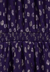 Ljubičasta tkanina s metalik zlatim i srebrnim točkicama, s akcentom na smuđi u struku i nabranim teksturama. Mekan, lagan materijal.