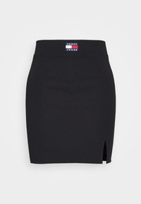 Svart randig kjol med en sidoflik, med en logotyp som säger "TOMMY JEANS" vid midjan. Slät textur, figurpassande design.