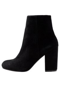 Bottine en daim noir à bout arrondi, talon bloc haut et texture lisse ; design épuré avec une silhouette ajustée.