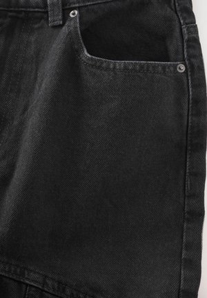 Juodos džinsinės šortai su priekiniu kišenėmis, dekoruotos siuvinėjimu ir metaliniu klyju. Audinys turi šiek tiek tekstūruotą paviršių.