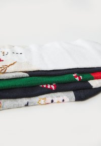 Meias coloridas empilhadas; brancas com design de inverno, verdes, cinza escuro e pretas. Tecido texturizado em mistura de algodão com padrões e acabamentos canelados.