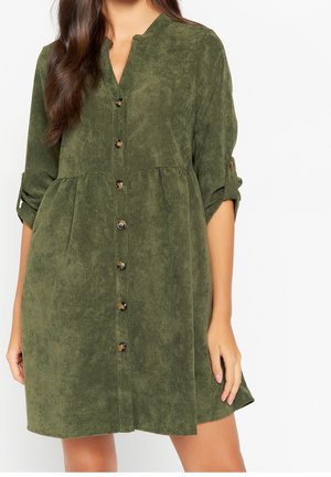Robe chemise verte texturée avec un col en V, manches longues retroussées, boutons devant et taille froncée, confectionnée dans un matériau doux.