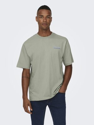 Lichtgroen katoenen T-shirt met een ronde hals en korte mouwen. Heeft een klein blauw logo op de linkerborst. Dragen met donkere jeans.
