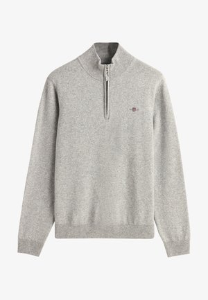 Pull en tricot gris clair à manches longues avec poignets et ourlet côtelés, col zippé au quart, et petit blason brodé rouge et marine sur la poitrine.