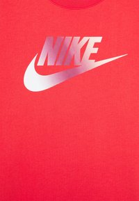 Czerwona bawełniana koszulka z gradientowym białym logo Nike. Projekt obejmuje klasyczny okrągły dekolt i krótkie rękawy.