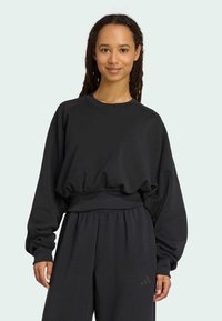 Sweatshirt noir à coupe décontractée et avec des poignets côtelés. Texture douce et taille élastique. Associé à un pantalon noir assorti.