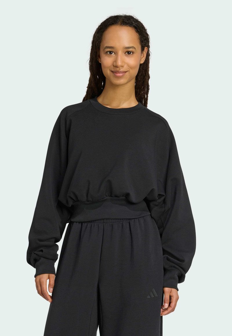 Sweatshirt noir à coupe décontractée et avec des poignets côtelés. Texture douce et taille élastique. Associé à un pantalon noir assorti.