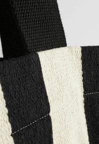 Zwart-witte gestreepte tote bag gemaakt van textuurstof, met sterke geweven hengsels en keurig gestikte naden.
