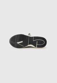 Black rubber shoe sole with textured surface, featuring a white midsole and distinctive patterns for traction and stability.