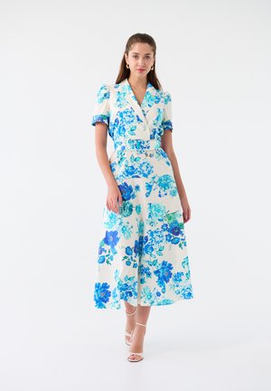 Abito floreale color crema con motivi floreali blu, maniche corte, vita con cintura e lunghezza midi. Tessuto morbido con una silhouette strutturata.
