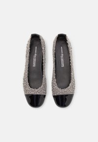 Paire de ballerines pour femmes en tissu gris texturé avec des bouts noirs brillants, vues de dessus sur un fond blanc.