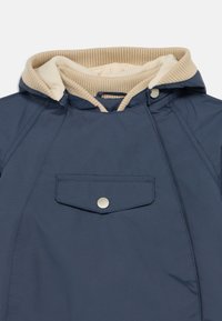 Σκούρο μπλε navy μπουφάν με εκρού εσωτερική επένδυση από fleece στην κουκούλα, διαθέτει μπροστινή τσέπη και ασημί κουμπιά με κούμπωμα. Υφασμάτινη υφή και λιτή, μοντέρνα σχεδίαση.