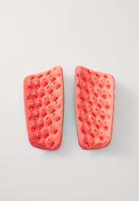 Deux tampons en silicone rouge avec une surface texturée et des trous, conçus pour une prise en main, affichant une forme contournée et des bords lisses.