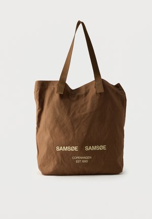 Brun stofnet med to håndtag og lys beige tekst "SAMSOE SAMSOE COPENHAGEN EST. 1993" på fronten.