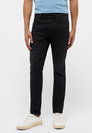 Black denim jeans with a slim fit, five pockets, and a button-zip closure. Paired with white sneakers and a light blue shirt.