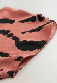 Tissu tricoté en rose poussiéreux avec des motifs abstraits noirs, présentant une texture douce et des bords arrondis et nets.