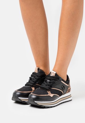 Černé tenisky s růžově zlatými akcenty, texturovanou látkou, tlustou bílou a černou podrážkou a černými tkaničkami. Detail s leopardím potiskem na boku.