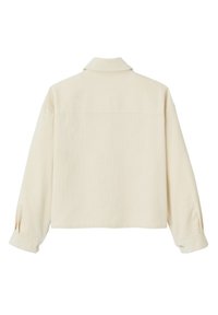 Veste en velours côtelé couleur crème avec un col, des manches longues et des détails de poignet boutonné. Présente une coupe droite et de subtiles lignes verticales.