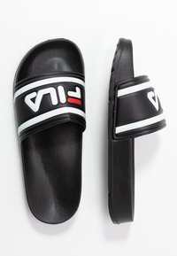 Zwarte slidesandalen met een gestructureerde zool, voorzien van een brede band met witte en rode FILA-logoaccenten en witte strepen aan de randen.