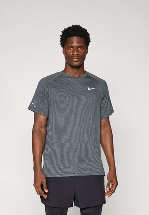 T-shirt de sport à manches courtes Nike en gris foncé, avec un motif texturé, un col rond et un petit logo blanc sur la poitrine.