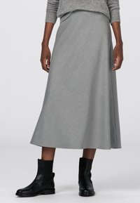 Harmaa A-linjainen midi-hame, joka on valmistettu teksturoidusta kankaasta. Hameessa on sileä vyötärö ja virtaava muotoilu, ja se on yhdistetty mustiin nilkkabootseihin.