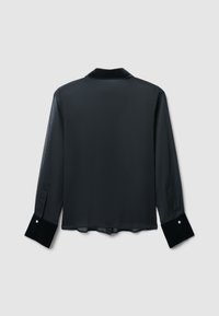 Camicia nera trasparente con maniche lunghe, polsini in velluto e orlo leggermente curvo. La vista posteriore mette in evidenza la morbida texture e il design elegante del colletto.