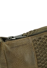 Borsa in pelle verde oliva con una texture a nido d'ape e un tirante della cerniera intrecciato. Presenta cuciture a contrasto e una cerniera in metallo.