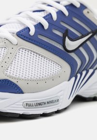 Blå og grå sportssko med mesh-overdel, læderdetaljer og struktureret sål. Bemærkelsesværdig brandingdetalje på sålen med teksten "FULL LENGTH NIKE AIR."